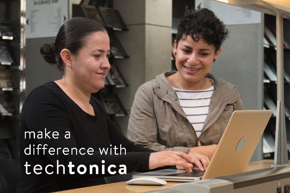 A mentor works with a participant at a laptop.